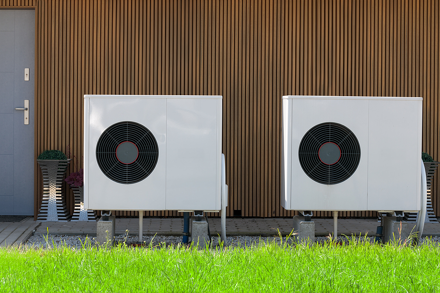 Two air source heat pump units on the side of a house